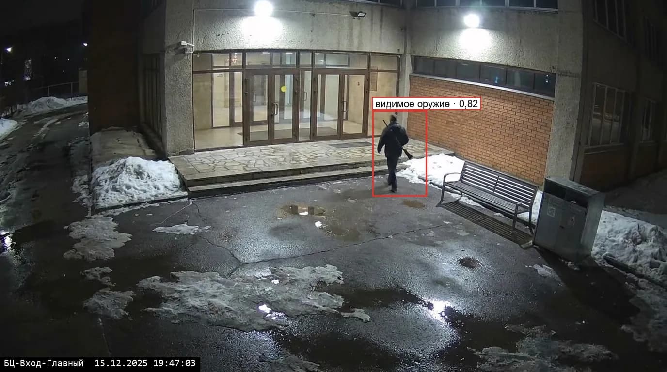 Вход бизнес-центра вечером: человек с ружьём на плече в рамке «видимое оружие»